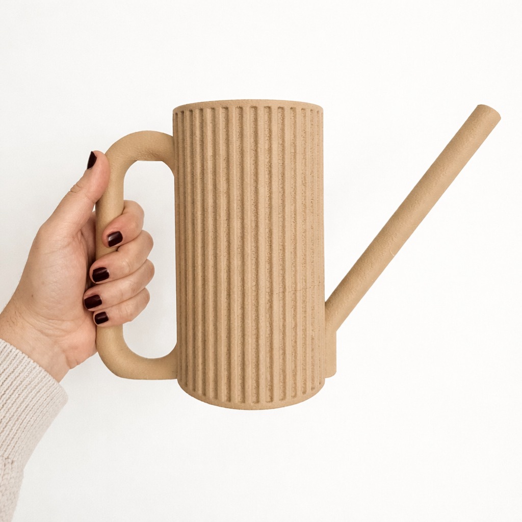 Hand holding the sand beige Collecticraft 3D printed watering can with ribbed body