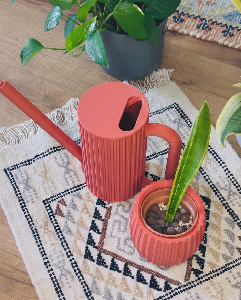 Red Teknospace watering can and matching planter styled with houseplants
